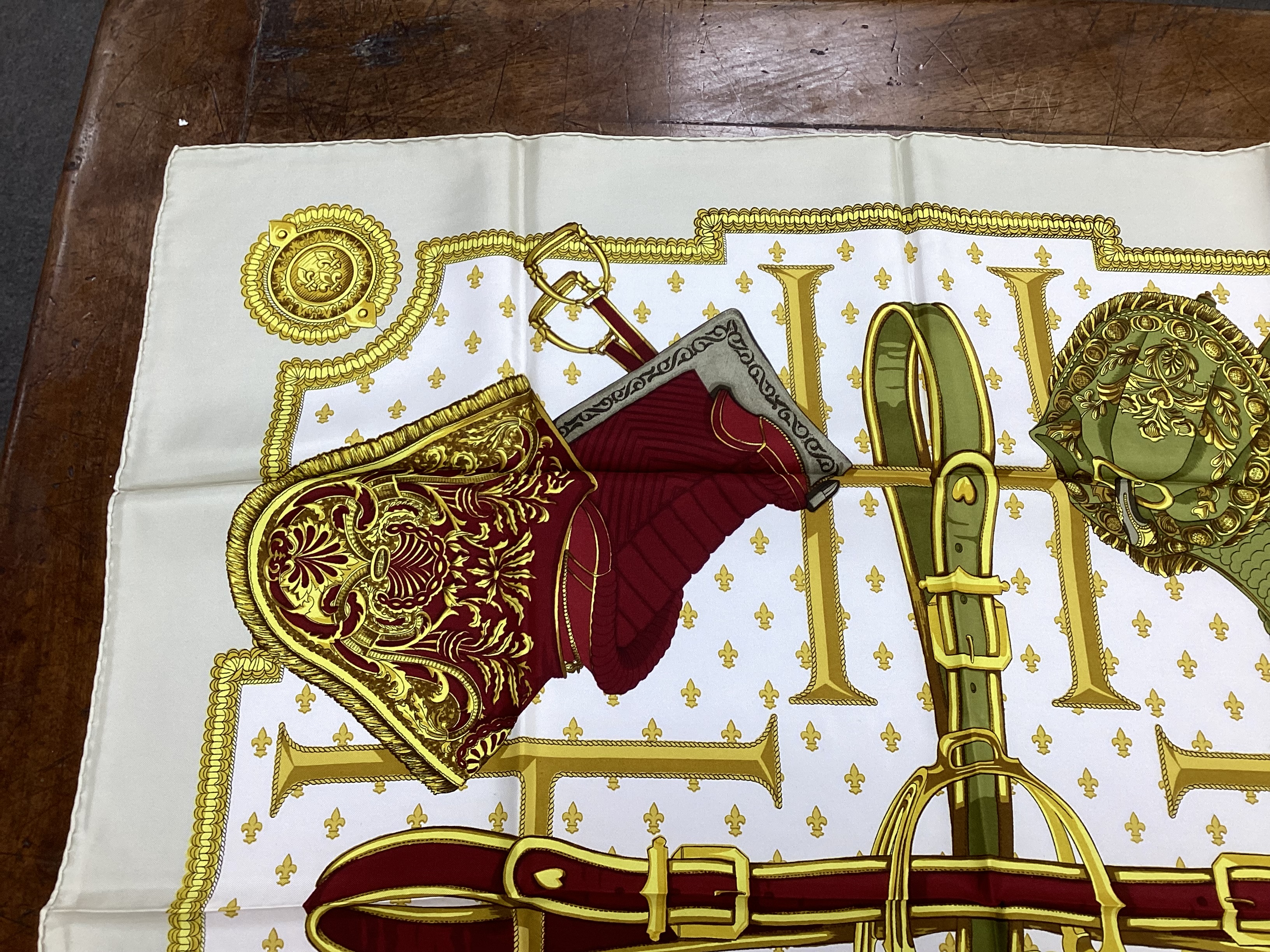 Four vintage Hermes silk scarves including one retailed by Harrods comprising, Selles A Housse, Roues de Canon, Passementerie and a rectangular Brides de Gala example